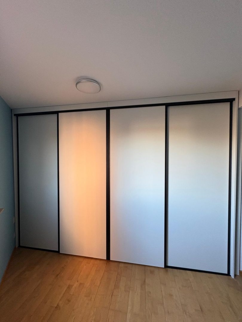 Schuifdeurgkast op maat met lichte panelen in slaapkamer
