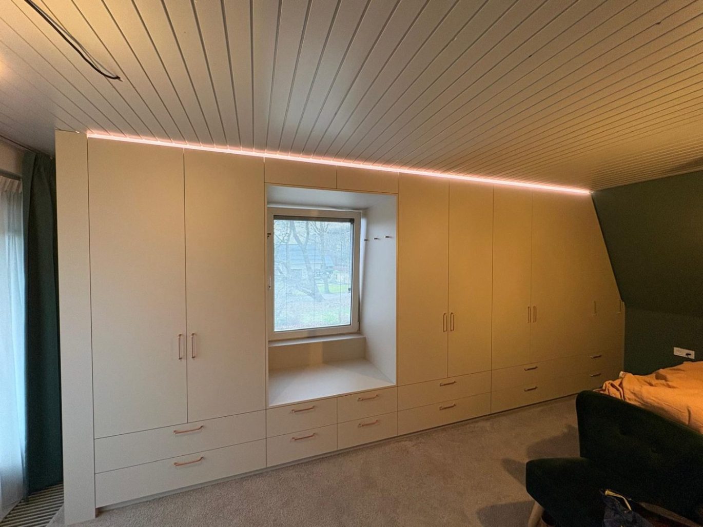 Inbouwkast op maat met LED-verlichting rondom dakraam in slaapkamer met schuin dak
